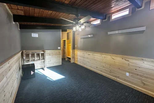 Cozy campground lodge room with built-in wooden bench seating, exposed beam ceiling, and skylight windows creating an inviting guest space at Sky Ranch Campground