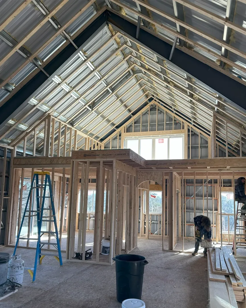 Professional barndominium framing construction showing exposed roof trusses, wall studs, and skilled craftsmen at work - demonstrating True North Construction's expert framing services for custom barndominiums and homes in Colorado